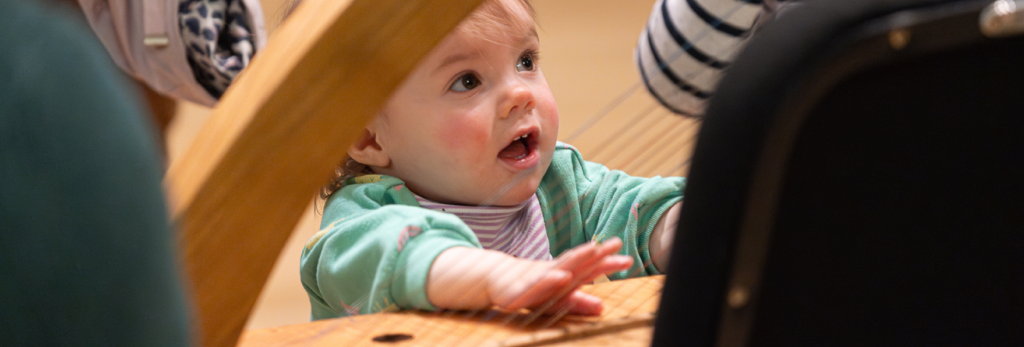 Baby examining a baroque era instrument at Indianapolis Baroque Orchestra family friendly concert